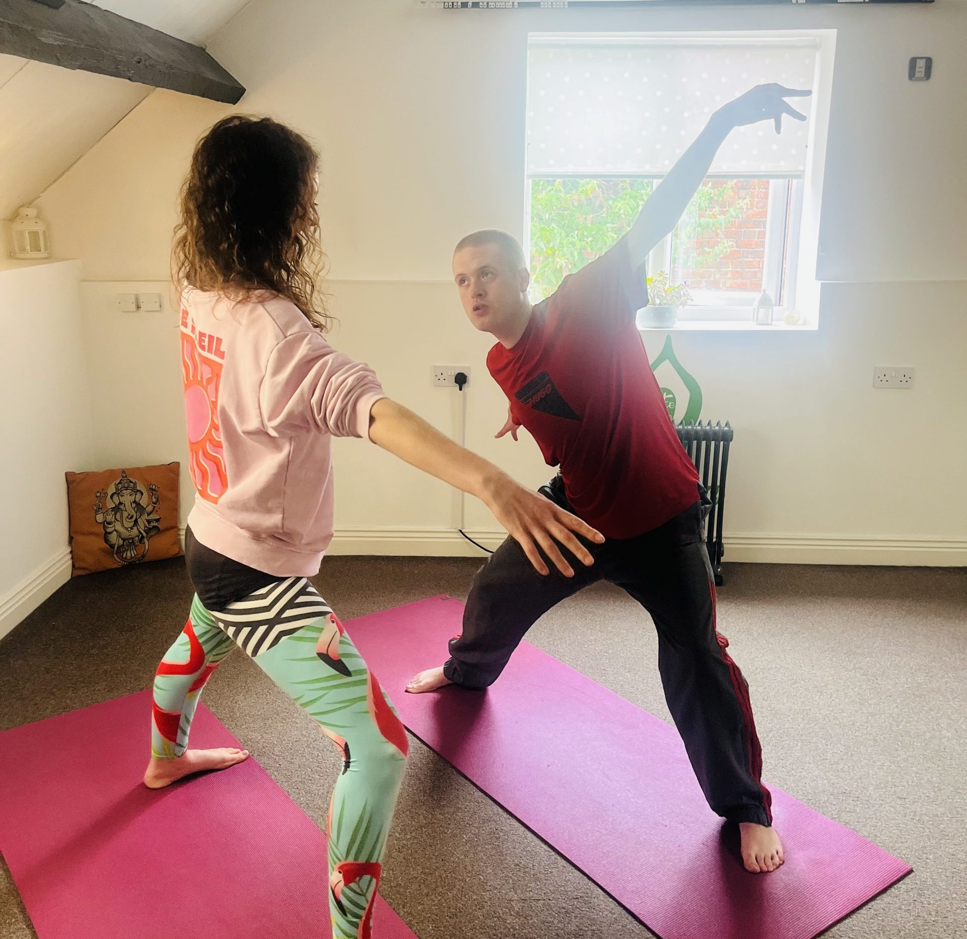 A woman and young man practicing yoga on mats in a studio.